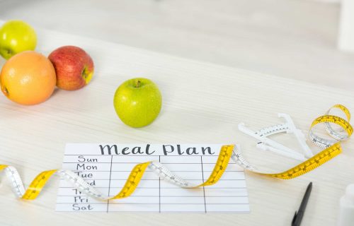 meal-plan-measure-tape-caliper-pen-and-fresh-fruits-on-wooden-surface